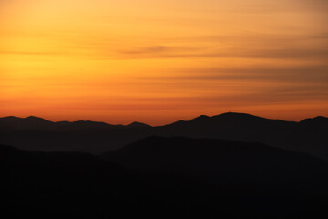Fototapeta premium Yellow and Orange Smear Over Mountain Ridge Silhouette