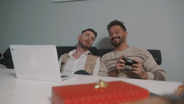 Happy gay couple or best friends playing video games. Gift in the foreground. High quality 4k footage