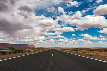 Empty road in the Arizona desert with big clouds and blue sky