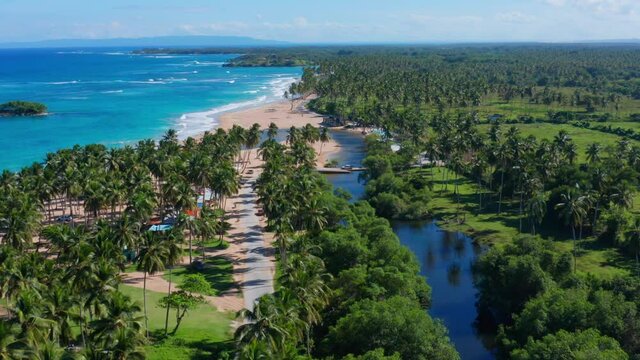 Aerial shot with drone in the coastal town Arroyo Salado in Cabrera Dominican Republic, view of the river parallel to the beach, tropical paradise, on a sunny day