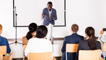 Portrait of cheerful successful man giving motivation training at conference hall