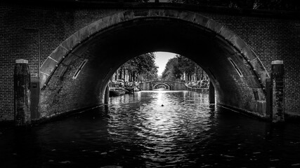Fototapeta na wymiar Black and White photo of View of seven historic bridges in a straight line over the Reguliersgracht, viewed from a canal boat in the Herengracht in historic Amsterdam