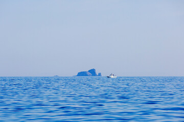 Fototapeta premium The white boat sails on a calm blue porch against the backdrop of the islands. Motor boat trips.