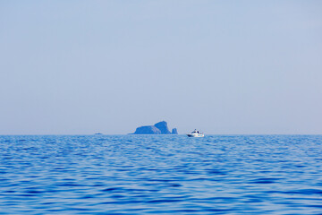 The white boat sails on a calm blue porch against the backdrop of the islands. Motor boat trips.