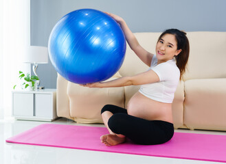 pregnant woman doing yoga exercise on fitness ball in living room at home