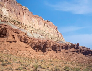 Fototapeta premium Sublime monoliths and towering sandstone cliffs on a hot partly cloudy summer day at Capitol Reef National Park in Southern Utah.