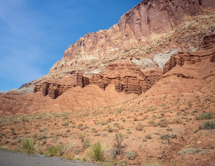 Fototapeta premium Sublime monoliths and towering sandstone cliffs on a hot partly cloudy summer day at Capitol Reef National Park in Southern Utah.