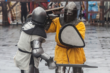 Two knights in medieval armor fight at the festival of historical reconstruction