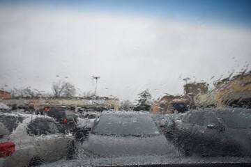 Parked in a strip mall in the rain looking out through a wet windshield -03