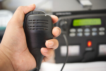 Close up of hand holding speaker ham radio transceiver base station.