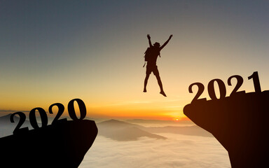Silhouette of man jump to New year 2021 at sunrise with mist cover moutain, Happy New year 2021 concept	
