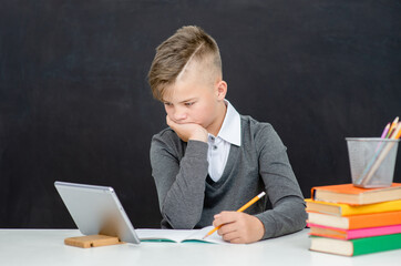 Pensive teen boy uses tablet computer. Distance education concept