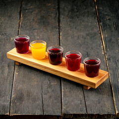 Selection of different natural fruit alcoholic tincture shots on the black wooden background