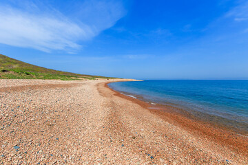 Deserted pebbly beach against the backdrop of a blue calm sea