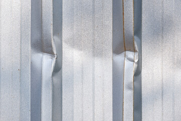 Close up dents on surface of corrugated metal wall