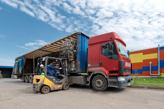 A forklift loads bales of compressed plastic bottles into a truck trailer. Transportation of triple plastic.