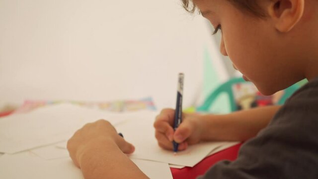 Over the shoulder take of caucasian key drawing on child's table at home 4K