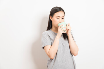 Gorgeous Asian woman drinking coffee and smiling standing over white background.