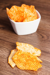 Potato crisps in bowl on wooden board, concept of unhealthy food
