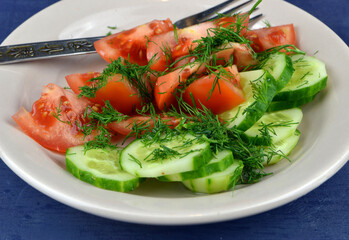 
a plate with cucumber and tomato salad is on the table
