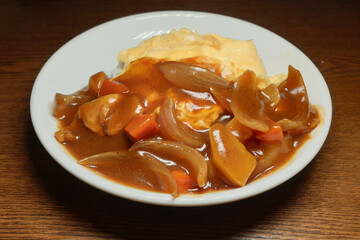 Japanese curry rice with chicken meat, egg, onion, carrot and potato close-up on a plate.