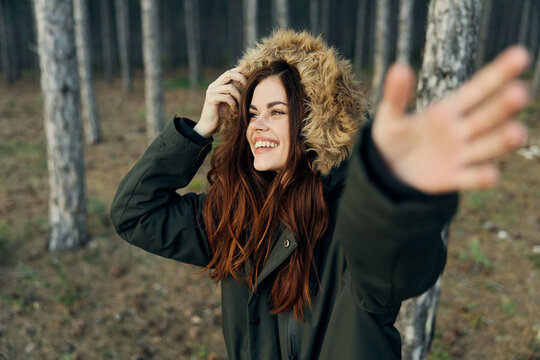 cheerful woman in a jacket in the forest gestures with her hands
