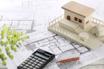 木でできた家の模型とマイホームの設計図のイメージ
