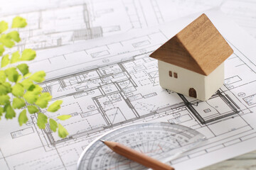 木でできた家の模型とマイホームの設計図のイメージ