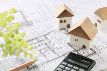 木でできた家の模型とマイホームの設計図のイメージ