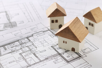 木でできた家の模型とマイホームの設計図のイメージ
