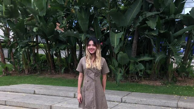 Chinese girl standing outside vlogging. 	China woman outdoors talking on camera. Cute girl takes video with point and shoot vlog camera making web video for fans.