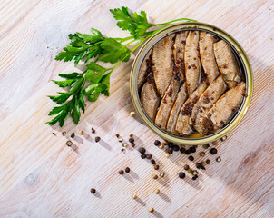 Picture of tasty small smoked sardines from Riga on background with greens and black pepper
