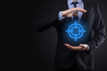 Targeting concept with businessman hand holding target icon dartboard sketch on chalkboard. Objective target and investment goal concept.