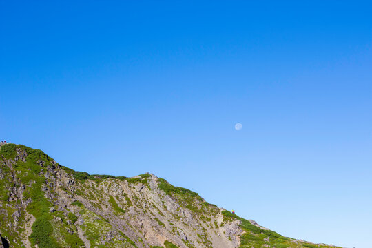 月が見える夏の青空と仙丈ケ岳