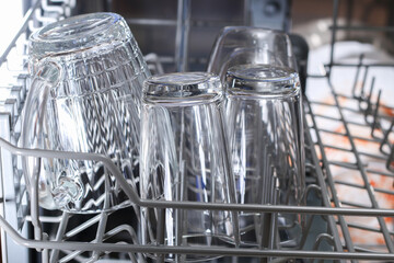 A man loads dirty dishes, plates, spoons, forks, cutlery into the dishwasher tray.