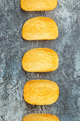 Top view of crunchy baked five chips lined up in a row on gray background stock image