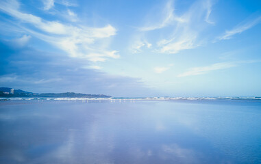 Obraz premium Evening view of the ocean with blue sky and cloud patterns and reflections.