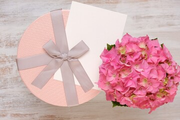 Holiday greeting card. Birthday blank postcard.Pink  box with bow , white card and  hydrangea flower on white shabby chic background.Women's Day, Mother's Day, Valentine's Day.copy space.