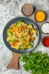Vertical view of healthy vegetable salad different spices and a bunch of green on white table