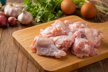 Fresh raw chicken drumettes on cutting board background.