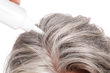 Mature man using serum for hair loss treatment on white background