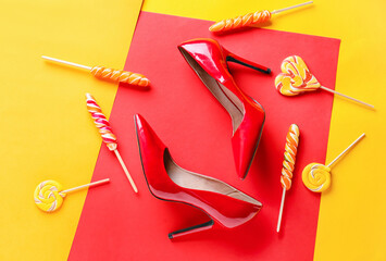 Stylish female shoes and candies on color background