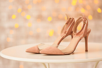 Naklejka premium Elegant pink suede high heels with clear straps on white table, fashionable footwear for special occasions, a bokeh light background adds a festive and glamorous atmosphere to the scene