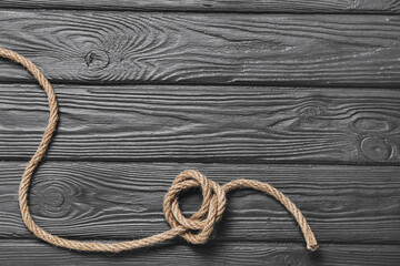 Rope with knot on wooden background