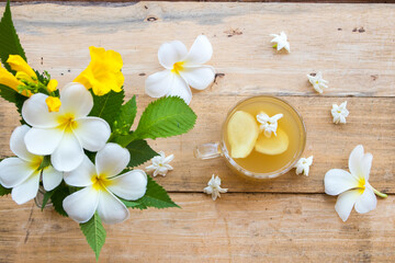 Obraz na płótnie Canvas herbal healthy drinks ginger syrup cocktail water for health care with ginger slice ,white flower frangipani arrangement flat lay style on background wooden