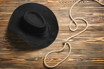 Cowboy hat and lasso on wooden background