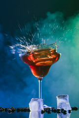 Glass of tasty coffee martini with splashes on dark background