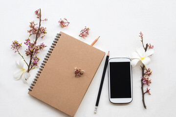 notebook planner ,mobile phone for business work with flower arrangement flat lay style on background white 