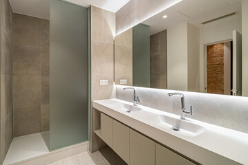Fototapeta na wymiar Modern tiled bathroom with a shower area, two sinks and a big wall mirror.