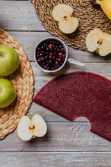 black currant fruit leather with fresh fruits on the wooden table. Round red fruit leather with black currant. Healthy food. Apples, bananas top view.
